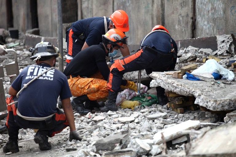 Rescuers try to uncover an unidentified man under slabs of cement in Cebu City, Philippines after a major 7.1 magnitude earthquake struck the region on October 15, 2013.  At least 20 people were killed on October 15 when the earthquake tore down buildings across three islands that are among the Philippines' most popular tourist attractions, authorities said. AFP PHOTO / Chester Baldicanto