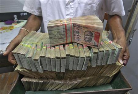 An employee poses with the bundles of rupee notes inside a bank in Agartala August 22, 2013. REUTERS/Jayanta Dey/Files