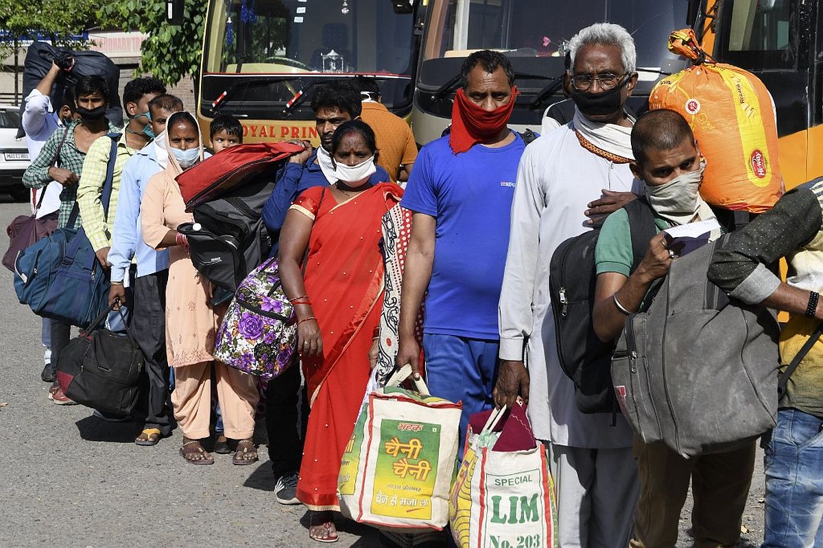Stranded migrant workers and their families queue as they wait for a medical screening before going to a railway station and board on a special train to Raebareli in Uttar Pradesh state after the government eased a nationwide lockdown imposed as a preventive measure against the COVID-19 coronavirus, at the Guru Nanak Auditorium, in Amritsar on May 18, 2020. (Photo by NARINDER NANU / AFP)