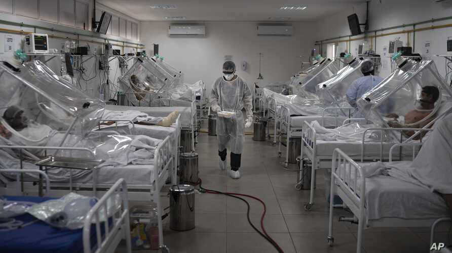 COVID-19 patients are treated inside a non-invasive ventilation system named the 'Vanessa Capsule' at the municipal field hospital Gilberto Novaes in Manaus, Brazil, Monday, May 18, 2020. The field hospital set up inside a school currently has nearly 150 beds and is operating near its limit as it treats patients both from the capital and from rural areas of the Amazon state. (AP Photo/Felipe Dana)